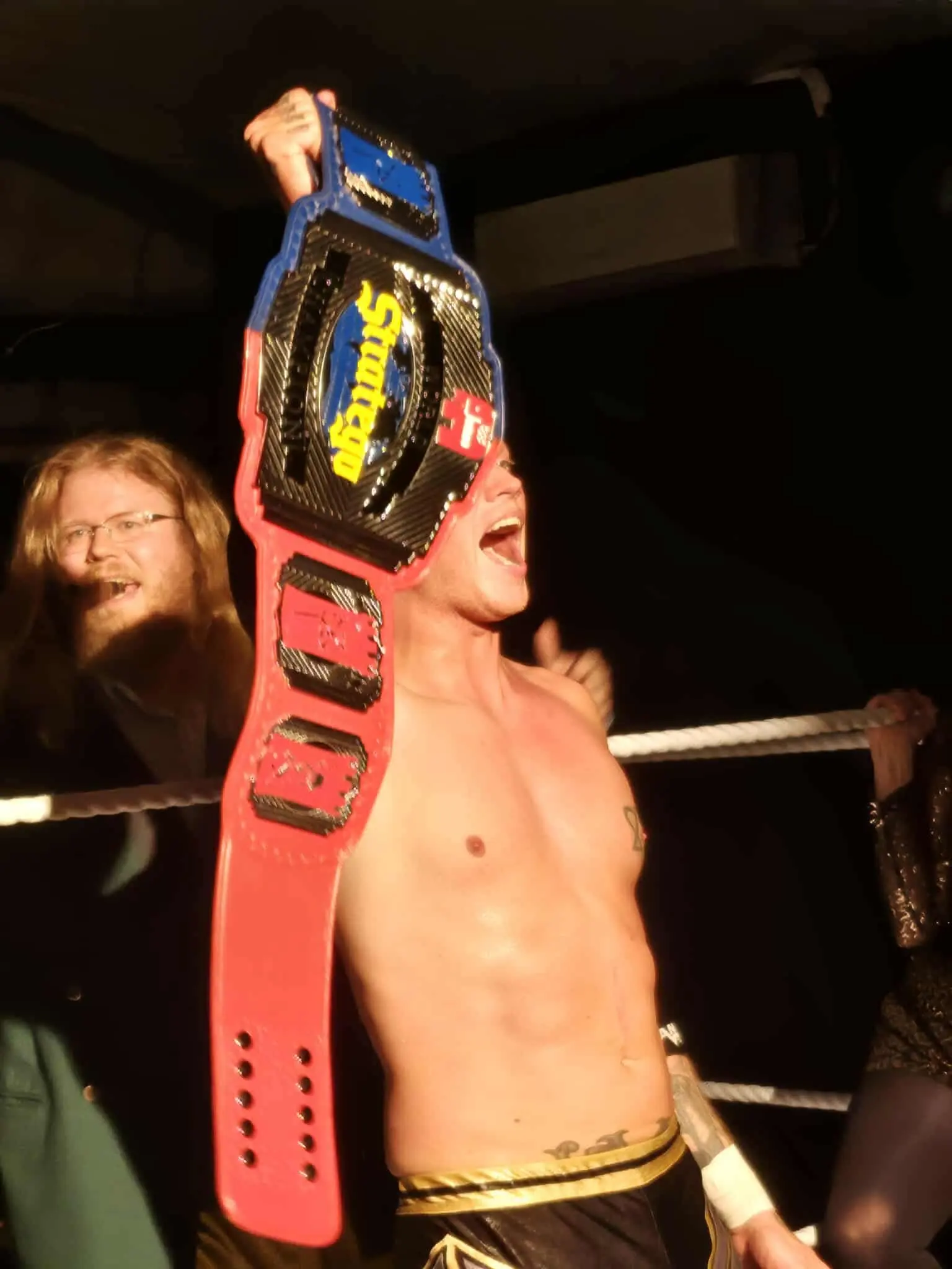 A wrestler raising a championship belt in the air